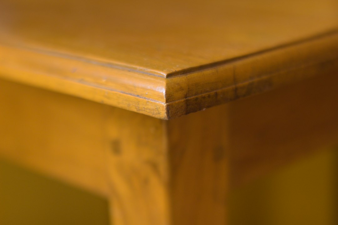 Home A close-up shot of a wooden table corner showcasing the natural grain and warm tones of the wood. This minimalist composition highlights the craftsmanship and simplicity of the design, offering a sense of warmth and tranquility.